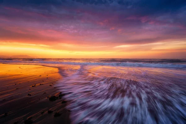 Strand bij zonsondergang met een golf — Stockfoto