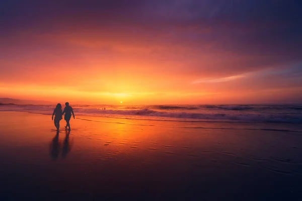 Пара прогулок по пляжу на закате — стоковое фото
