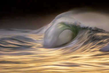 Photo of a big wave breaking at sunset with in camera panning te clipart