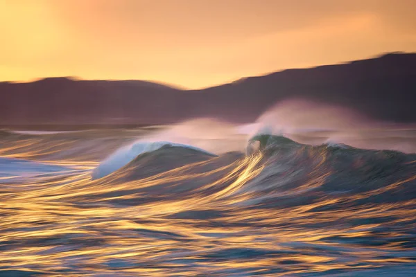 Фотография большой волны, ломающейся на закате, с камерой в руках — стоковое фото