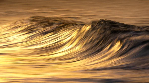 Photo of a wave at sunset with in camera panning technique — Stockfoto