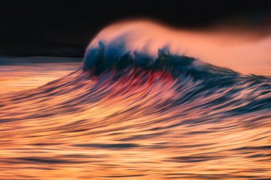 wave with spray breaking at sunset with in camera panning techni clipart