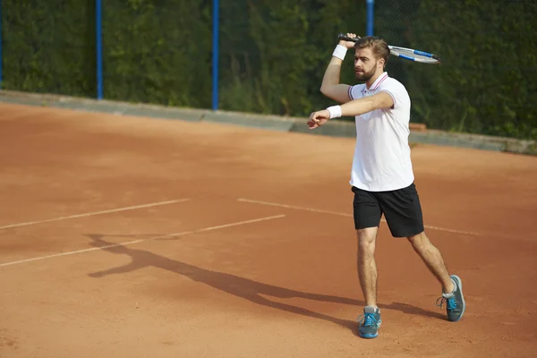 Мужчина играет в теннис в солнечный день — стоковое фото