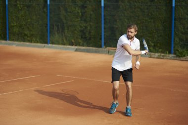 Genç adam tenis oynuyor.