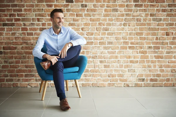 Zakenman die zich voordeed op blauwe leunstoel — Stockfoto