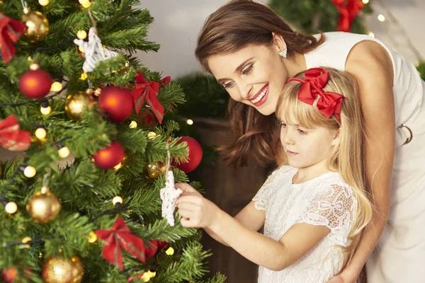 Lilla flickan att hjälpa mamma att dekorera julgran — Stockfoto