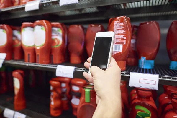 Usando o telefone celular durante as compras — Fotografia de Stock