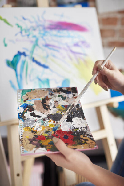 Женщина рисует на мольберте
