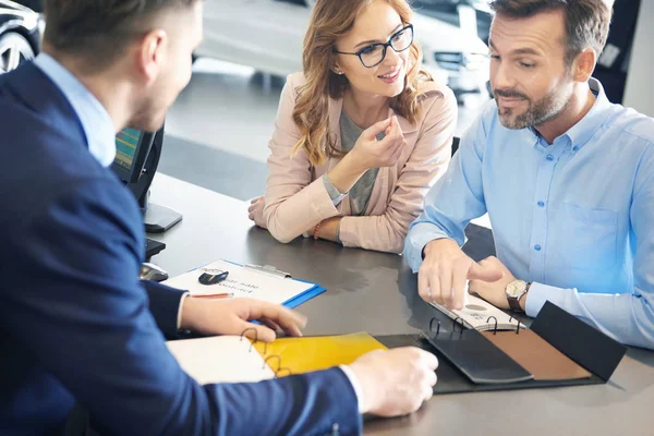 Ehepaar und Autoverkäufer im Geschäft — Stockfoto