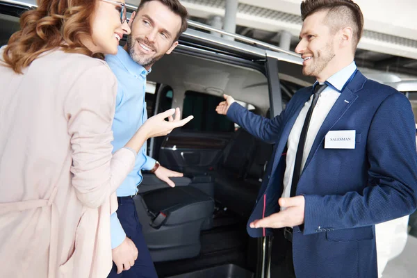 Pareja y vendedor de coches en la tienda — Foto de Stock