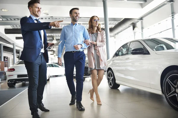 Coppia e venditore di auto in negozio — Foto Stock