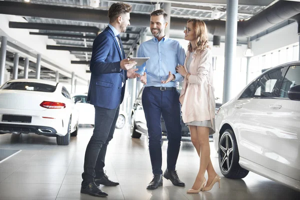 Pareja y vendedor de coches en la tienda — Foto de Stock