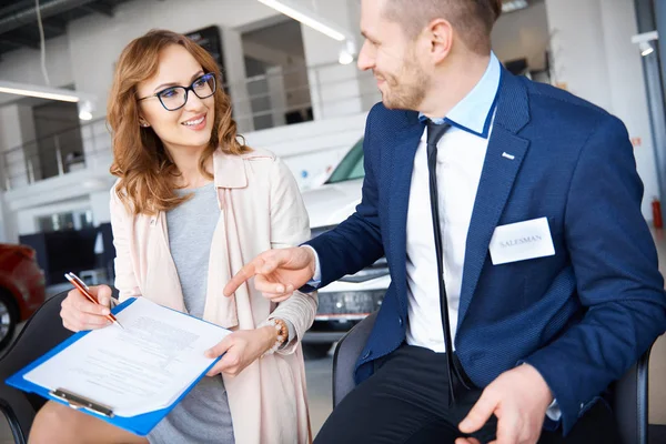 Kvinna och bil försäljare i showroom — Stockfoto