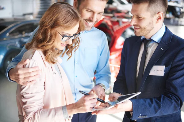 Ehepaar und Autoverkäufer im Geschäft — Stockfoto