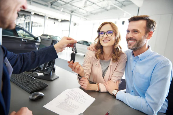 Paar en auto verkoper in de winkel — Stockfoto