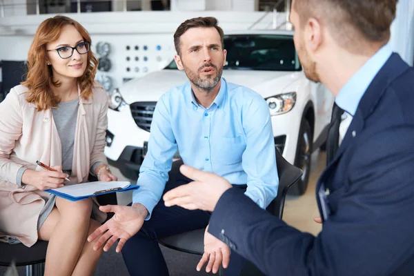 Ehepaar und Autoverkäufer im Geschäft — Stockfoto