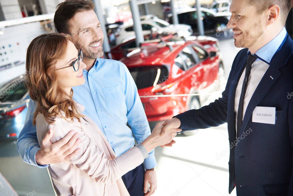 Couple and car salesman in shop