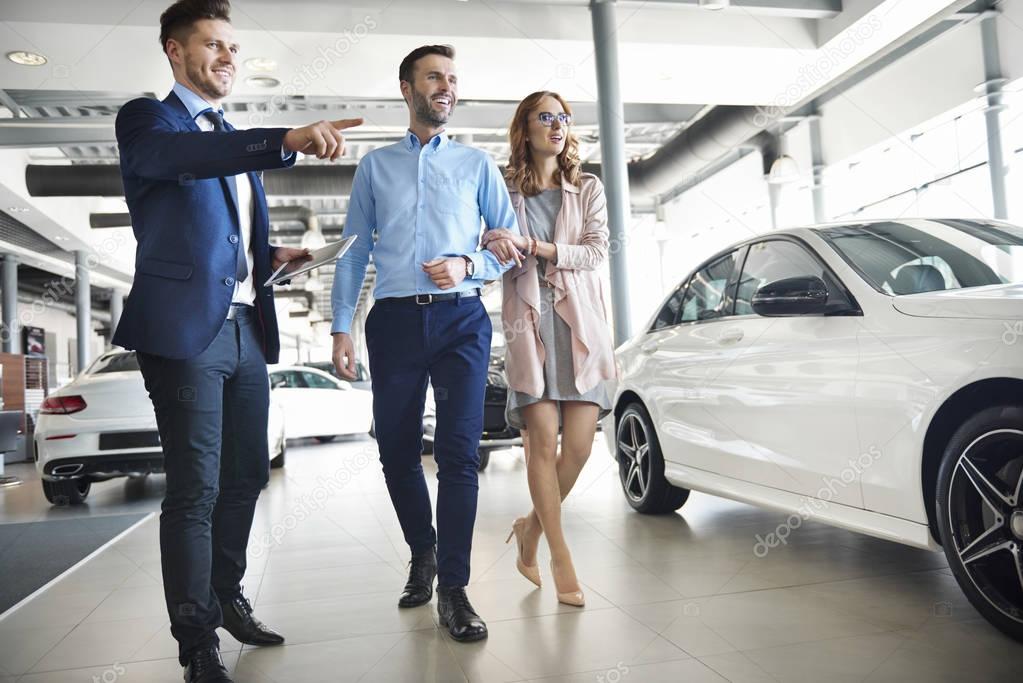 Couple and car salesman in shop