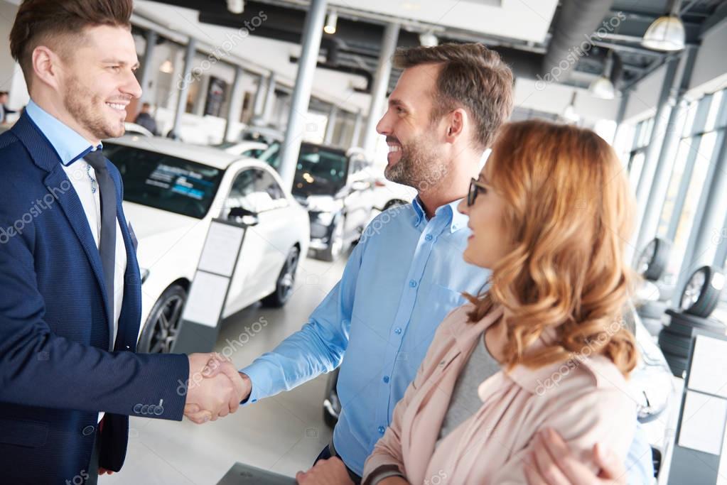 Couple and car salesman in shop