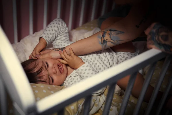 Мать на детской кроватке по ночам — стоковое фото