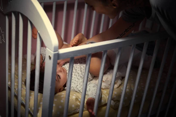 Mother by baby crib at night — Stock Photo, Image