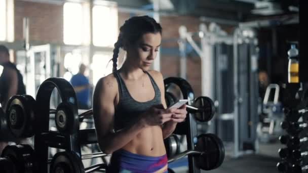 Kvinnan använder mobiltelefon på gym — Stockvideo