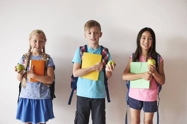 Sırt çantaları holding kitaplar ve elma çocuklar — Stok fotoğraf