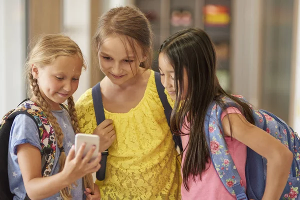 Schoolmeisjes permanent en kijken op smartphone — Stockfoto