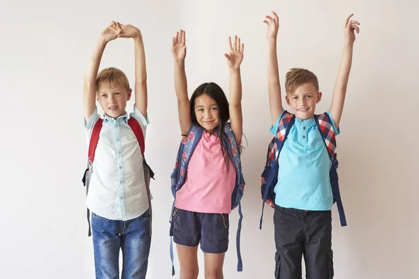 Pupilas com mochilas em pé com as mãos para cima — Fotografia de Stock