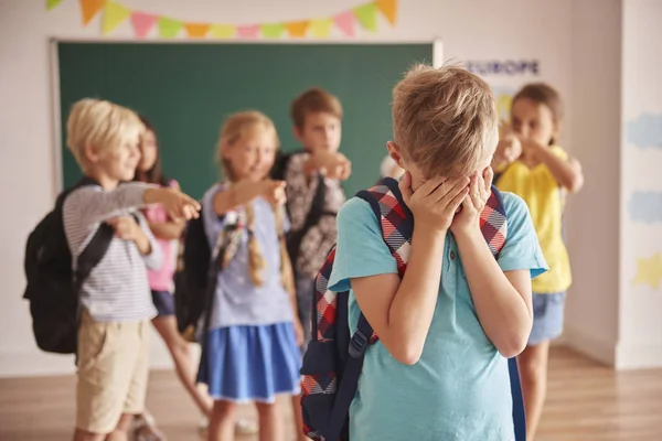 Boy standing sad in front of classmates — Stock Photo, Image