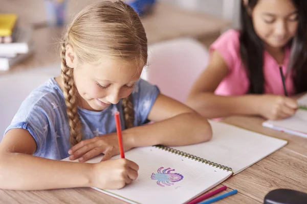 Écolières dessin tandis que assis dans la salle de classe — Photo