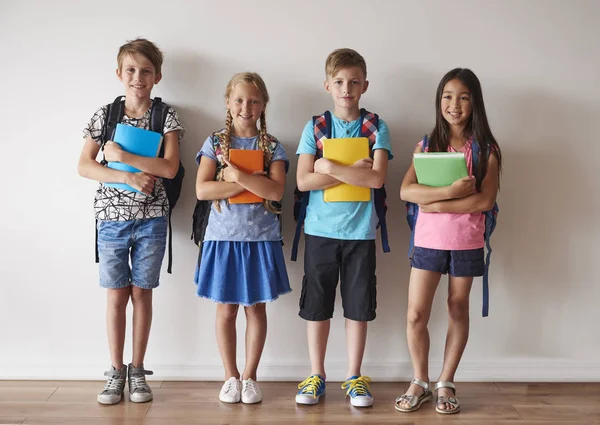 Smiley kids with backpacks holding books — Stock Photo, Image