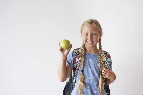 Skolflicka med ryggsäck holding apple — Stockfoto