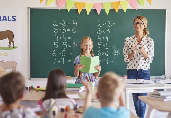 Skolflicka stående nära blackboard med lärare — Stockfoto