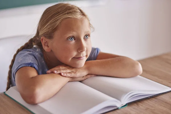 Schoolgirl leaning on book in classroom — Stock Photo, Image