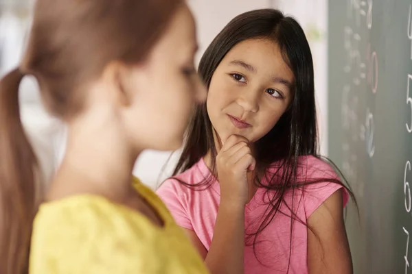 Colegiala mirando a compañero de clase cerca de escritorio — Foto de Stock