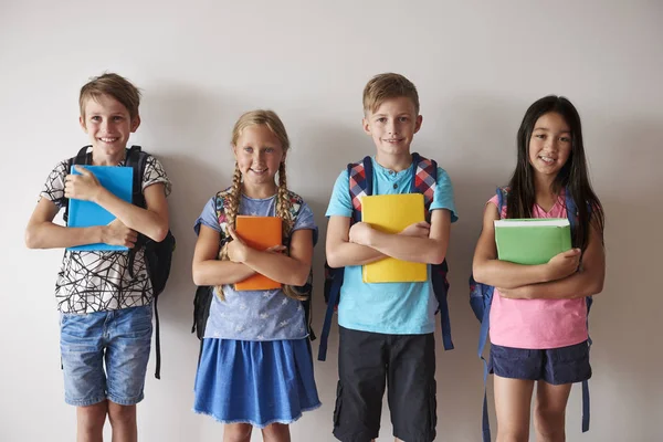 Niños sonrientes con mochilas sosteniendo libros —  Fotos de Stock