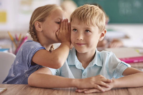 Niño y niña susurrando en el aula — Foto de Stock