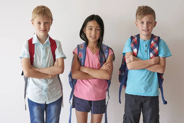 Leerlingen met rugzakken permanent met gekruiste armen — Stockfoto