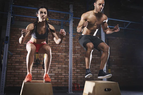 Sportliches Paar springt in Turnhalle auf Bahnsteigen — Stockfoto