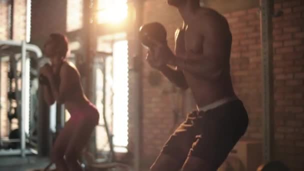 Casal fazendo agachamentos com kettlebells no ginásio — Vídeo de Stock