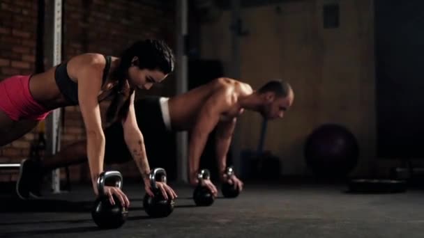 Couple doing push ups with kettlebells — Stock Video