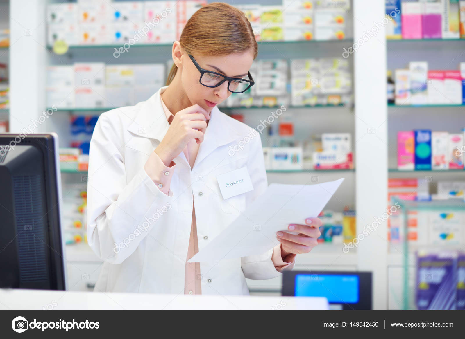 Female pharmacist checking documents at drugstore Stock Photo by