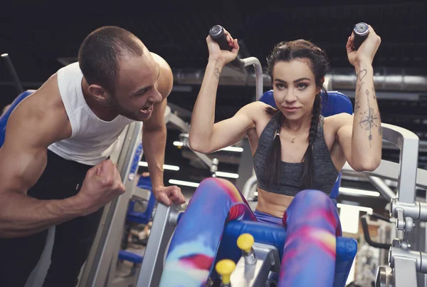 Personal trainer guding jovem mulher no ginásio — Fotografia de Stock