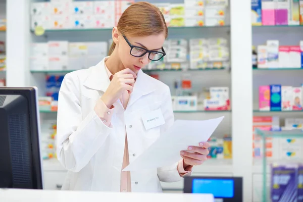 Farmacéutica revisando documentos en farmacia — Foto de Stock