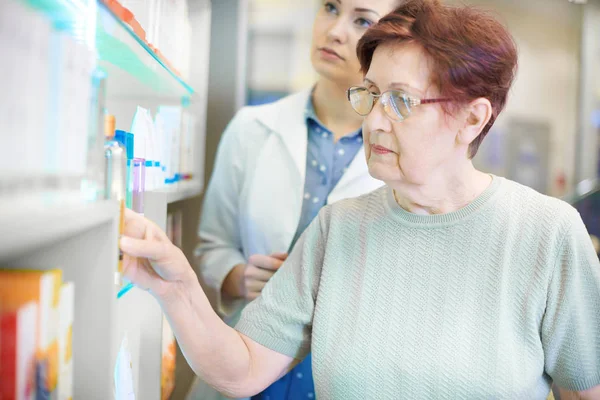 Farmacêutico ajudando a mulher idosa com receita médica — Fotografia de Stock