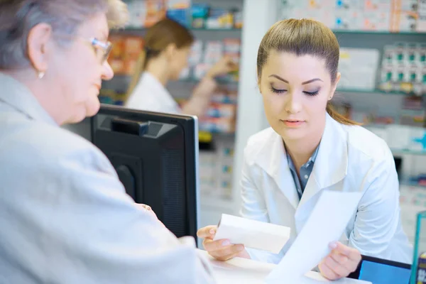 Rijpe vrouw product met de apotheker bespreken — Stockfoto