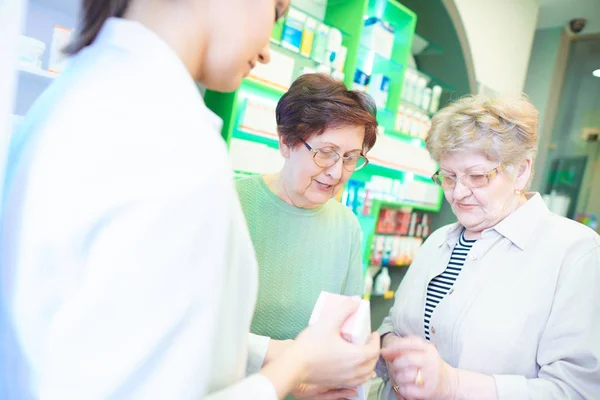 Літні жінки порівнюють ліки в аптеці — стокове фото