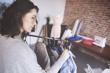 Genç moda tasarımcısı yeni kıyafetler üzerinde çalışıyor. 