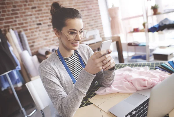 Jeune tailleur souriant utilisant un smartphone — Photo